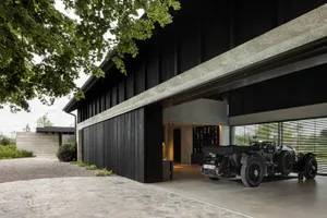 Modern garage with black metal walls and concrete floor, featuring a classic car inside.