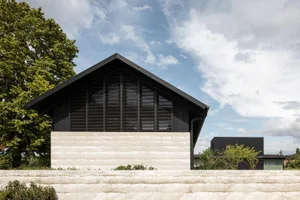 Modern house exterior with concrete base and black wooden slats on the upper structure.