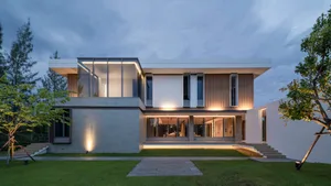 Modern house with glass walls, concrete base, and wooden accents.