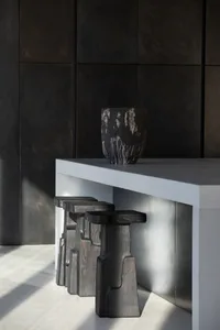 Modern kitchen interior with concrete countertops, stools, and wall panels.