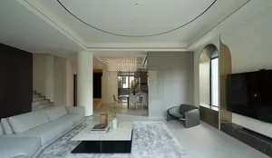 A modern living room with a minimalist design, featuring concrete walls, a white marble coffee table, and a ceiling light fix