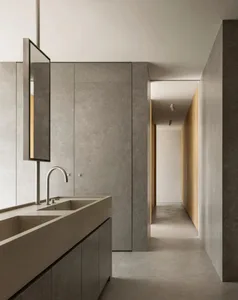 Modern minimalist bathroom featuring concrete tile flooring and walls, with a sleek faucet and minimalist design elements.