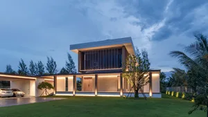 A modern residential exterior with glass, concrete, and wood materials at dusk.