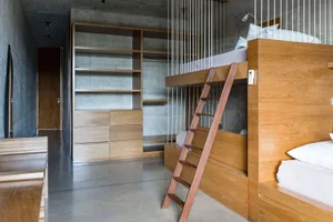 Industrial-style bedroom featuring concrete walls and wooden furniture with a ladder.