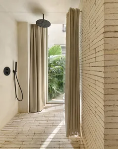 Minimalist outdoor shower area with sandstone brick walls and concrete floor.