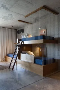 A modern bedroom with wooden bunk beds and a concrete floor.