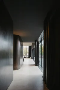 A modern, dark interior corridor with large glass windows and black curtains.