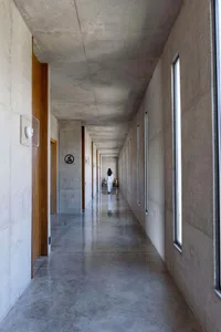 A modern interior space with a concrete hallway and large windows.
