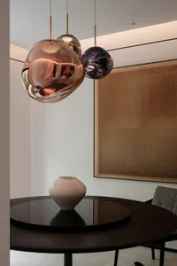 A modern living room featuring glass pendant lights hanging above a black round table.