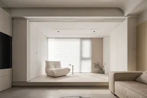 Modern, minimalist living room with neutral-toned furniture and decor, featuring a sleek, white armchair and a sofa in a cozy