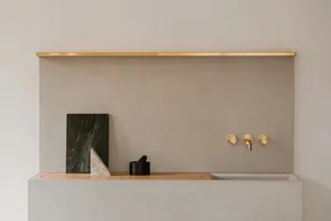 A minimalist bathroom featuring concrete, brass, and marble materials.