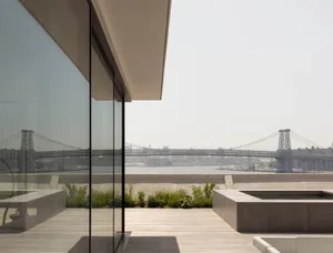 Modern residential patio with glass walls and concrete deck featuring a view of the bridge.