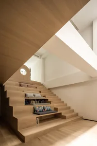 Modern wooden staircase featuring built-in seating and shelving.