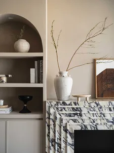 Marble vase with branches and books on a shelf, marble fireplace, and marble walls.