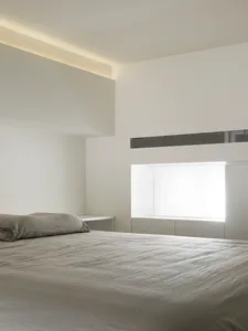 Modern minimalist bedroom featuring textured concrete surfaces and natural light.