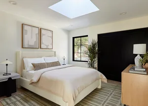 A minimalist bedroom featuring white soft furnishings, a bed with a white mattress, and a large window with a black frame.