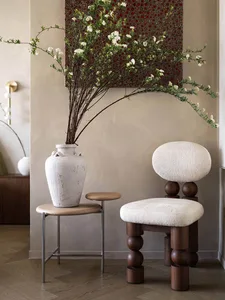 A modern interior design with a wooden chair featuring round, wooden legs and white upholstered seating, accompanied by a whi