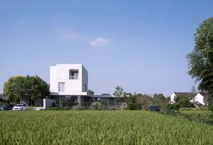 Modern white concrete residential home exterior with green grass and trees in the foreground.