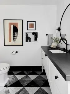 Minimalist bathroom featuring black and white checkered marble tiles, a white ceramic toilet, a white vanity with black count