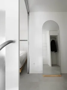 Minimalist bedroom interior with metallic accents and concrete floor.