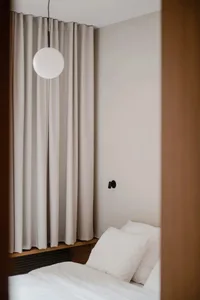 A minimalist bedroom with soft lighting features clean lines, soft grays, and a simple wooden bed frame.