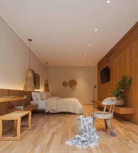 A minimalist bedroom featuring wooden furnishings, including a bed, chair, and hanging lamps.