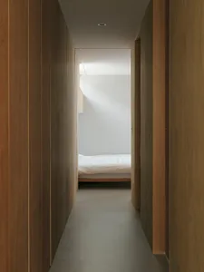 A modern bedroom with wooden walls and a white bed.