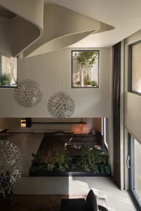 A modern living room featuring metal pendant lights, a concrete floor, and various plants.