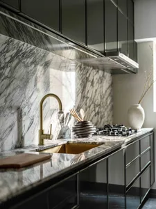 Modern kitchen with black cabinetry and marble countertops and backsplash.