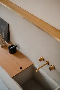 Modern kitchen featuring a wooden countertop, concrete sink, and brass faucet