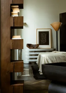 A modern minimalist bedroom featuring a white marble table, a wooden bookshelf, and a dark wood bathtub.