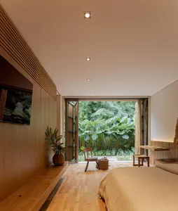 A minimalist bedroom featuring wooden elements and an open layout looking out to a lush green garden.