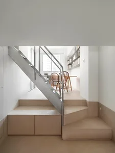 Minimalist concrete staircase with metal railings and integrated seating in a living space.