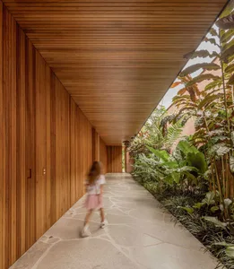 A minimalist residential interior featuring wood elements and a long corridor with greenery.