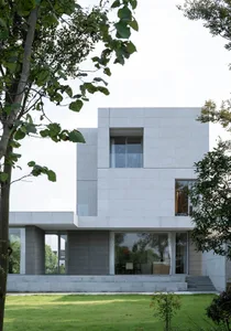 Modern residential building with white concrete exterior and large windows.