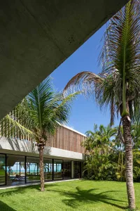 Modern minimalist house exterior featuring concrete and glass materials under a clear blue sky.