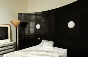 Modern bedroom with black accent wall and white concrete floor and walls