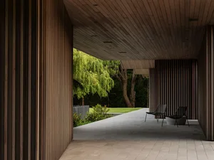 Modern exterior design featuring a wooden facade, concrete floor, and lush greenery.