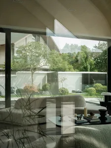 Modern living room featuring a contemporary sofa upholstered in gray fabric, with a glass coffee table and a view of a landsc