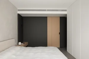 A modern minimalist bedroom featuring a white bed with a tufted headboard, a small wooden nightstand, and a sliding door with