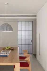Modern minimalist kitchen features sleek wooden furniture and a geometric glass divider.
