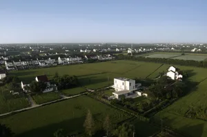 Aerial view of a rural settlement with green fields and white houses.