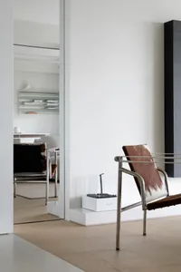 Modern minimalist living room with metal and leather furniture, clean lines, and white walls.