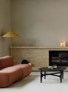 A minimalist living room featuring a cozy sofa, a stone fireplace, and a modern coffee table with a plant.