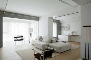 Modern minimalist living room with white furniture, fabric upholstery, and wooden floors.