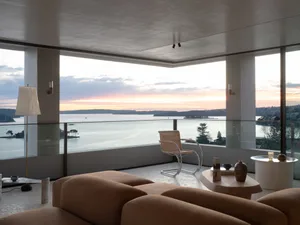 A minimalist living room featuring a modern leather sofa, a glass coffee table with ceramic ornaments, and a view of the sea 