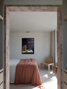 A minimalist bedroom with marble accents and a wooden chair.