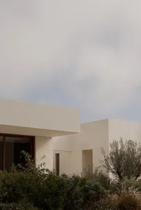 A minimalist residential exterior featuring concrete materials and a modern design.