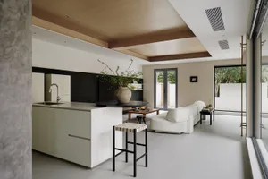 A modern minimalist residential kitchen featuring white marble countertops and black acrylic cabinets.