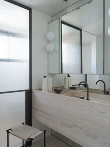 Modern bathroom with stone interior design, featuring a large sink and large mirror.